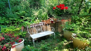 A garden with a metal bench surrounded by potted plants and greenery.