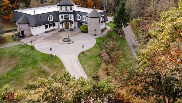 Ein großes, zweistöckiges Gebäude mit Innenhof, umgeben von Bäumen und einem gepflegten Rasen.