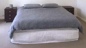 Un dormitorio con una cama, dos mesitas de noche y un enchufe.