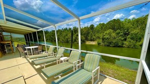 A covered outdoor area with lounge chairs and a table, overlooking a river and forested area. - Stunning Lakeview Villa (Davenport)