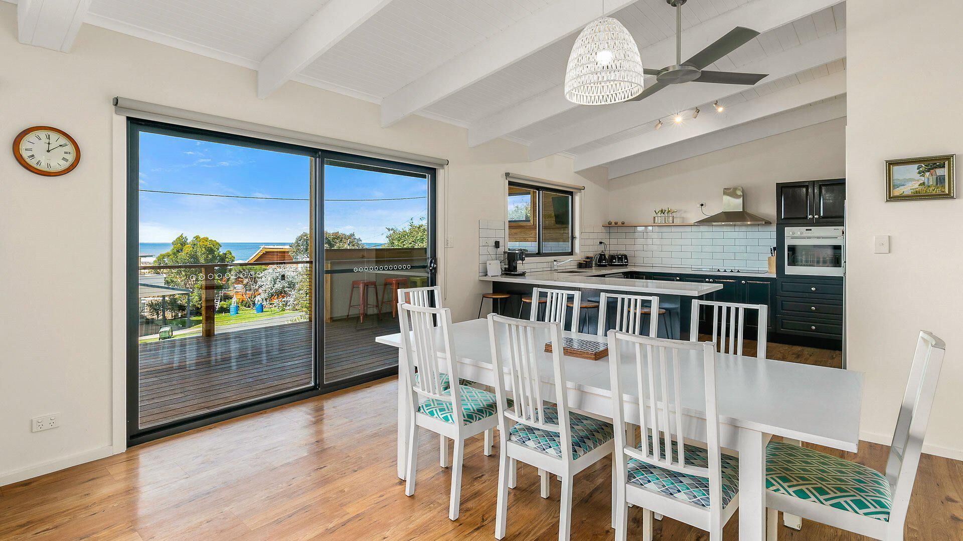 A modern kitchen with a large island, white cabinetry, and a view of the outdoors.