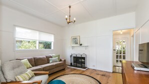 A living room with a sofa, a chair, a fireplace, and a television. - Grand Vue (Lorne)