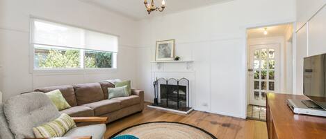 A living room with a sofa, a chair, a fireplace, and a television.
