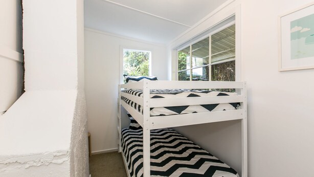 A bunk bed with a zebra-patterned bedspread, a window with a view of greenery, and a framed picture on the wall. - Grand Vue (Lorne)