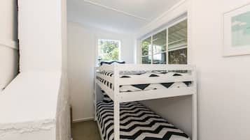A bunk bed with a zebra-patterned bedspread, a window with a view of greenery, and a framed picture on the wall.