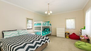 Een kinderkamer met een bed, stapelbedden, een kast en een raam.