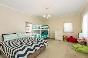 A child's bedroom with a bed, bunk beds, a dresser, and a window.