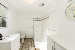 A bathroom with a toilet, sink, and shower area.