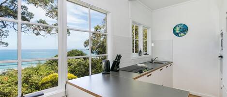 Una cocina moderna con vista al mar, ventanas amplias y un diseño minimalista.