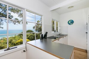 Una cocina moderna con vista al mar, ventanas amplias y un diseño minimalista.