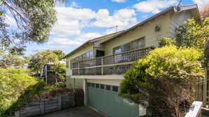 Een tweelaags huis met een groene garage, een balkon op de bovenverdieping en een oprit die naar de garage leidt.