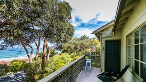 A balcony with a view of the ocean, a chair, and a door with a geometric design. - Grand Vue (Lorne)