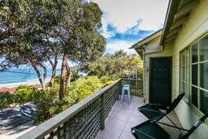 A balcony with a view of the ocean, a chair, and a door with a geometric design. - Grand Vue (Lorne)