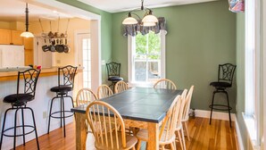 Un comedor con una mesa y sillas, una cocina al fondo y una ventana con cortinas.