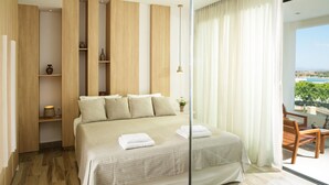 A modern hotel room with a large bed, wooden paneling, a small table, and a view of the outdoors.