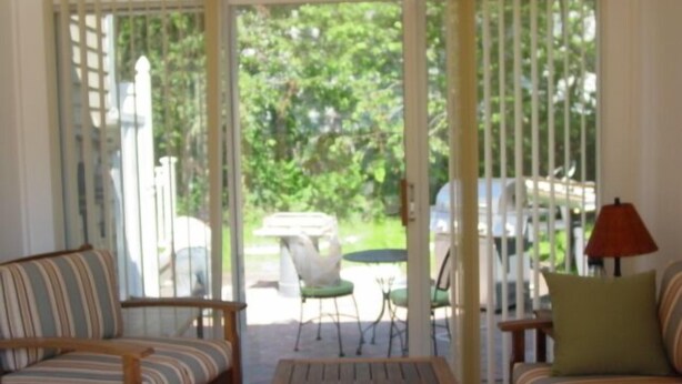 A room with a wooden coffee table, striped sofas, a red lamp, and a view of a garden through a glass door. - SHORT WALK TO BEACH Central A/C (Dennis Port)