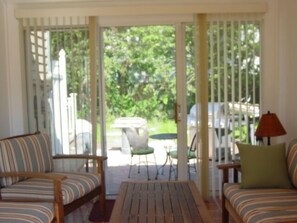 A room with a wooden coffee table, striped sofas, a red lamp, and a view of a garden through a glass door. - SHORT WALK TO BEACH Central A/C (Dennis Port)