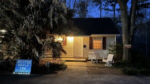 A small house with a porch, a welcome sign, and a sign that reads "BREATHE DEEPLY YOU FOUND US".