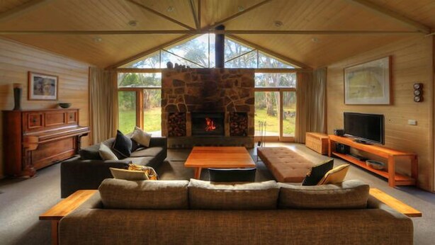 Una sala de estar acogedora con chimenea de piedra, un sofá, una mesa de centro y un televisor.