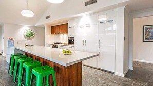 A modern kitchen with a central island, wooden cabinets, and green bar stools. - Lilywood—Minutes from Wineries & Yallingup Beach (Yallingup)