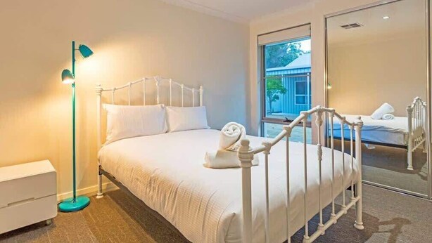 A bedroom with a bed, a nightstand, a floor lamp, and a large window. - Lilywood—Minutes from Wineries & Yallingup Beach (Yallingup)
