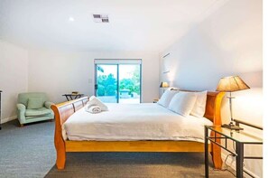 A hotel room with a bed, a chair, a lamp, and a view of the outdoors.