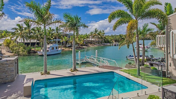 Une piscine avec vue sur un port de plaisance et des palmiers.