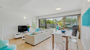Un salon moderne avec un téléviseur, un canapé et un coin repas.