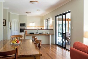 Una cocina moderna con comedor, un ventanal grande y puerta corrediza de vidrio que da a un espacio exterior.