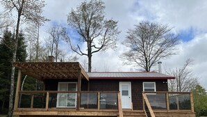 Une cabane en bois dotée d’un balcon, d’un escalier et d’une porte.