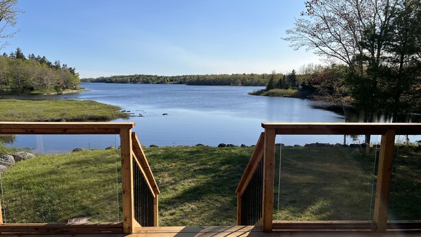 Une terrasse en bois offrant une vue sur un lac paisible, entouré d’arbres.