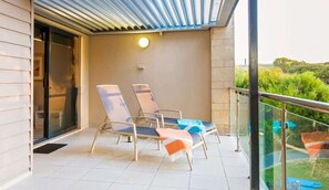 A balcony with two lounge chairs, a glass door, and a view of greenery. - Surfside 9: In the Idyllic Yallingup Beach Scene (Yallingup)
