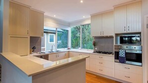 Una cocina moderna con muebles blancos, una isla central, horno integrado y una ventana que proporciona luz natural.