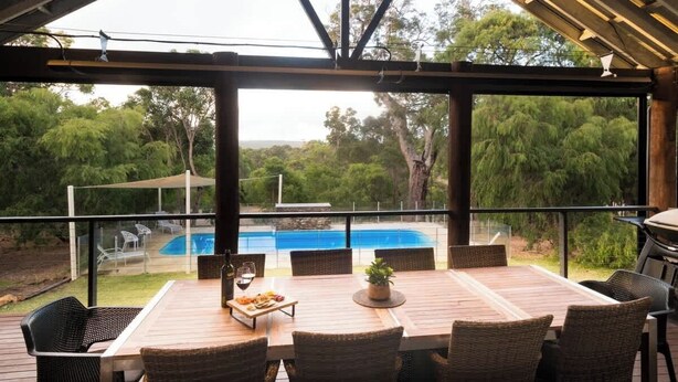 Un área de comedor al aire libre con vistas a una piscina y abundante vegetación.