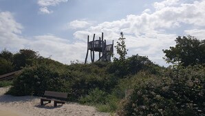 Una platja sorrenca amb una banca de fusta i una escultura singular al fons.