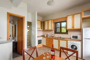 Une cuisine avec des meubles de rangement en bois, un évier, une cuisinière, un four à micro-ondes et un lave-linge.