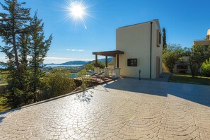 Un patio dallé avec une pergola, une vue sur les montagnes et un bâtiment doté d’un toit plat.