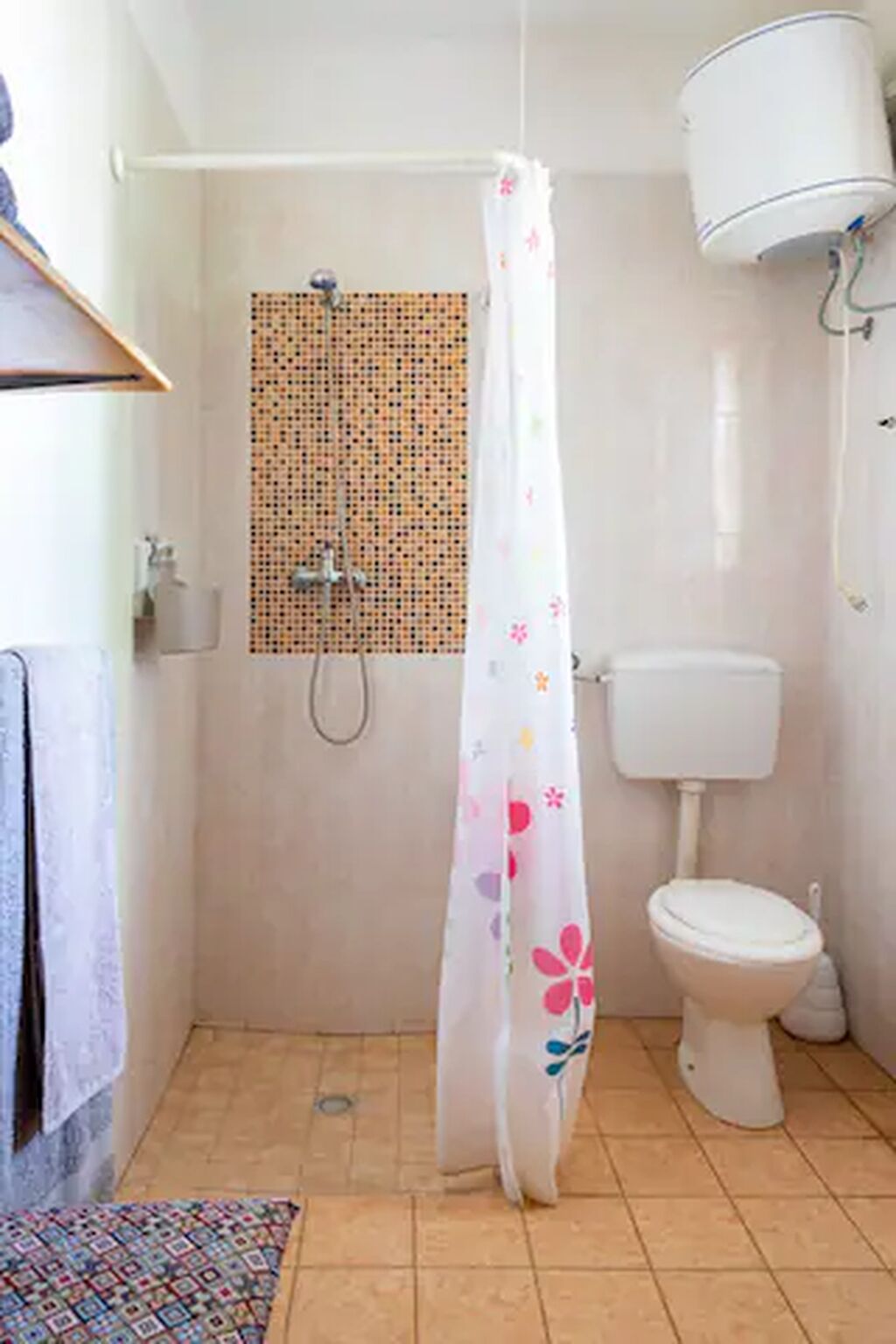 Un baño pequeño con ducha, inodoro y pared con diseño.