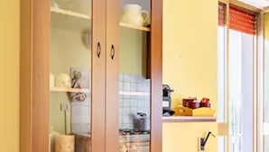 A wooden cabinet with glass doors and drawers, located in a room with yellow walls and a tiled floor. - villa 10 min from Gallipoli | entire structure | swimming pool and large garden (Sannicola)