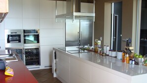 Una cuina moderna amb armaris blancs, electrodomèstics d'acer inoxidable i un taulell vermell.