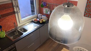 Eine moderne Küche mit einer Spüle aus Edelstahl, einem Wasserkocher und einer Obstschale auf der Arbeitsfläche.