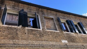 Ein Backsteinhaus mit vielen Fenstern, von denen einige mit Fensterläden versehen sind, und einem strahlend blauen Himmel.