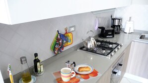 A modern kitchen with a gas stove, coffee maker, and a colorful kitchen towel. - apartment under the hill of San Miniato (san miniato)