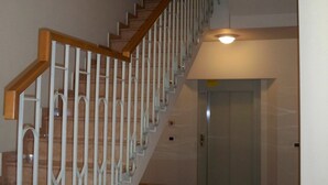 A staircase with wooden handrails and metal balusters, leading to an elevator.