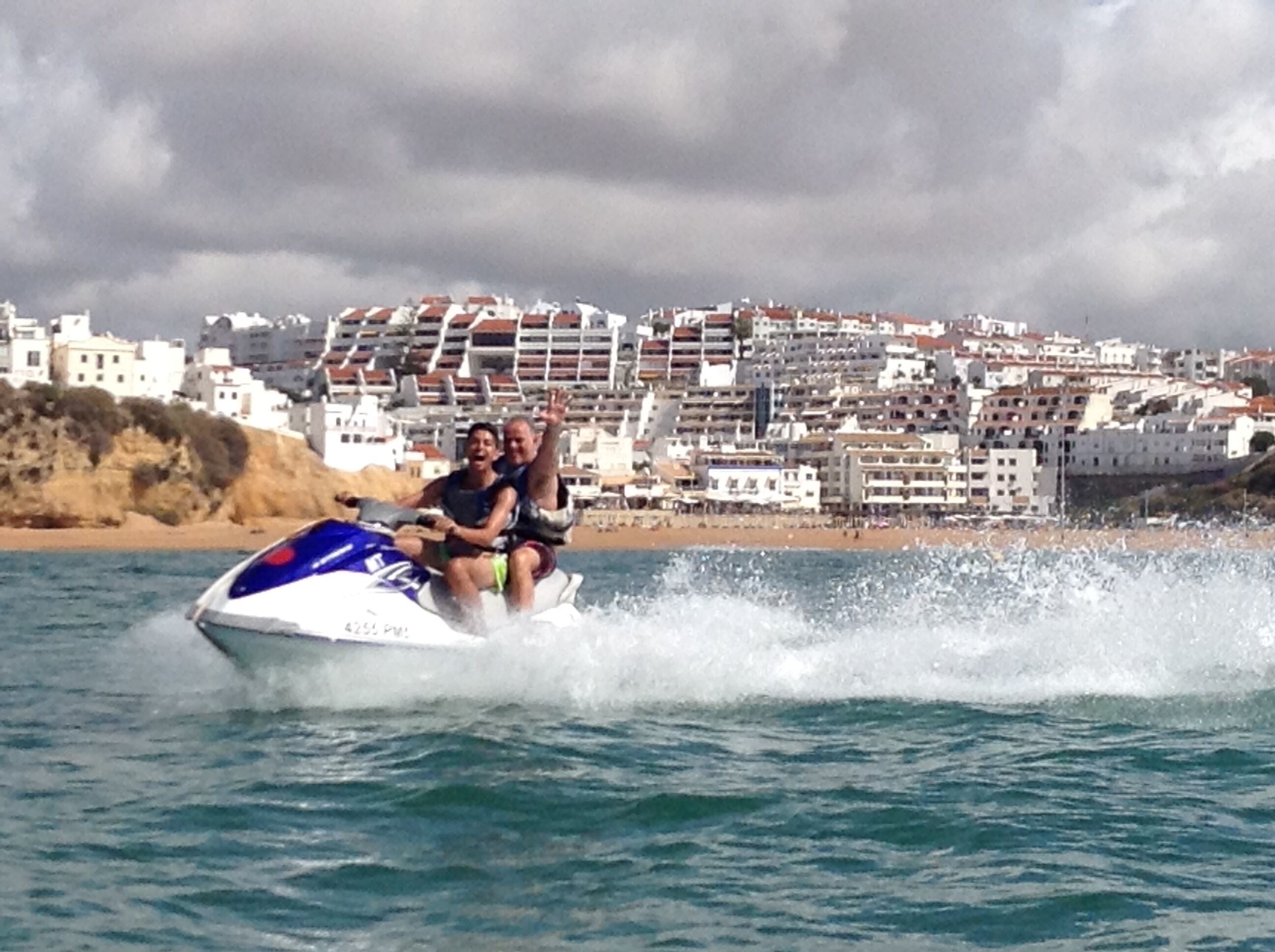 Un jet ski sur l’eau, avec une ville côtière en arrière-plan.