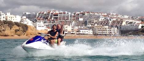 Un jet ski sur l’eau, avec une ville côtière en arrière-plan.