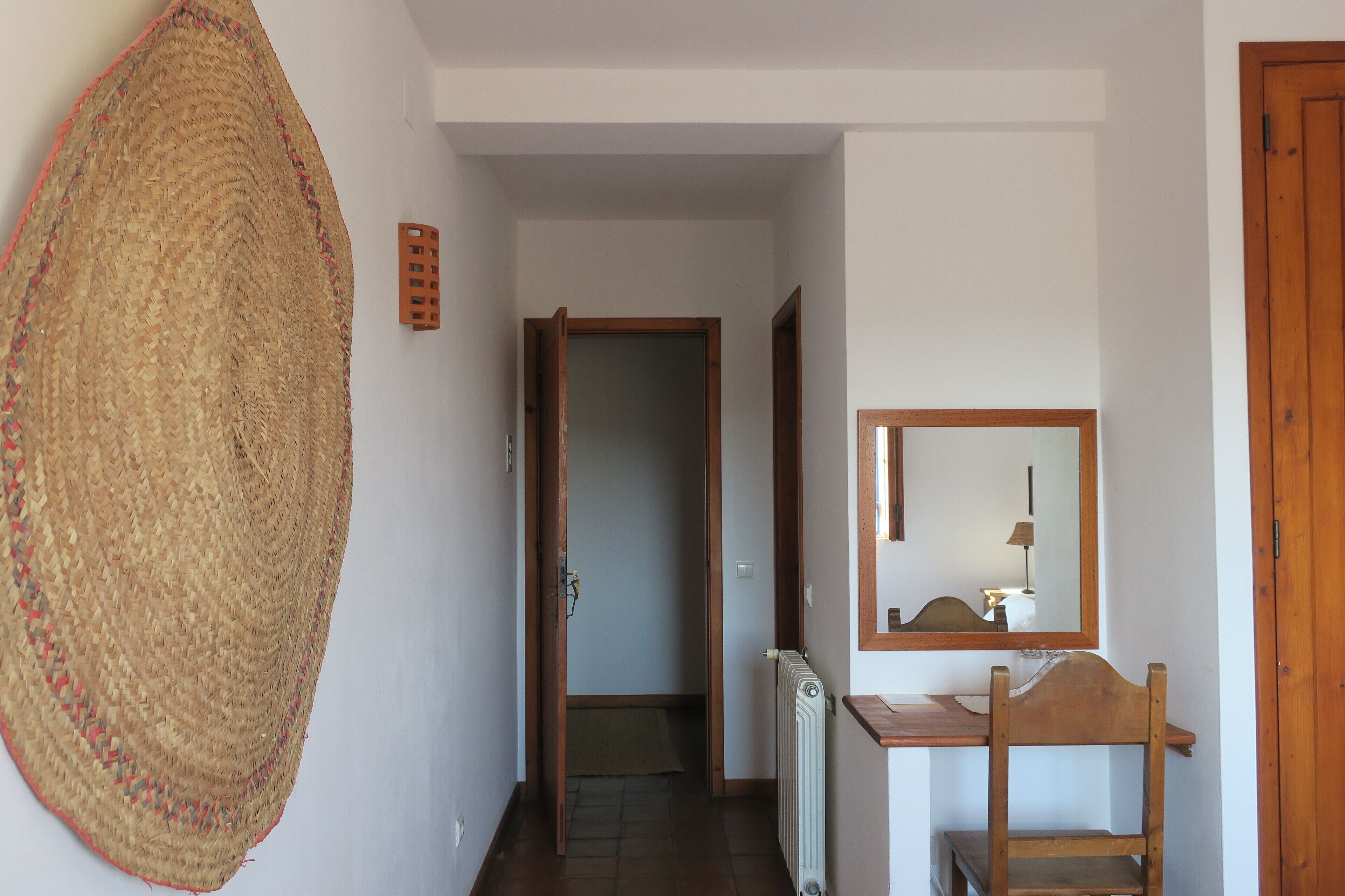 A hallway with a woven basket, a wooden door, a radiator, and a mirror on the wall.