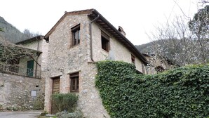 Um edifício de pedra com telhado inclinado, porta de madeira e antena parabólica.