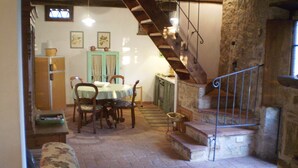 Uma área de refeições com mesa, cadeiras, escada e parede de pedra.