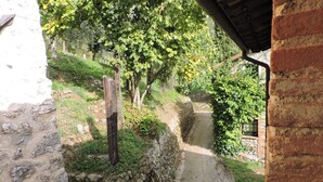 Um caminho de pedra estreito, ladeado por vegetação e um edifício rústico.